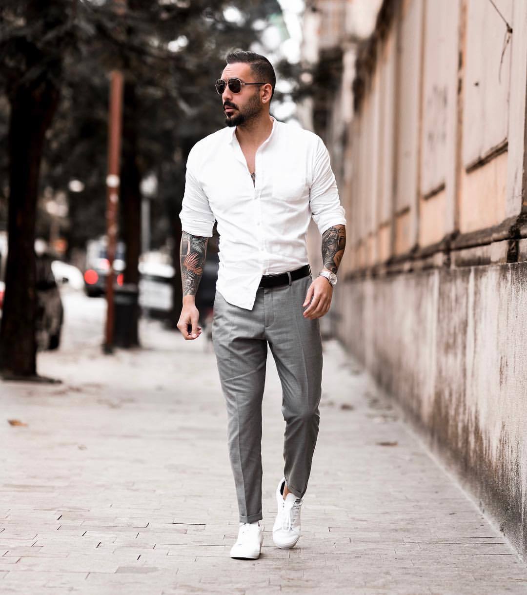 Модный лук: белая рубашка с длинным рукавом, серые классические брюки, белые кожаные низкие кеды, черный кожаный ремень