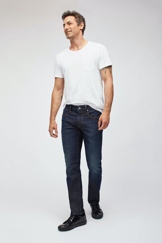 Как носить темно-синие джинсы с черными низкими кедами мужчине