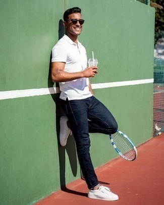 Как носить белые кожаные низкие кеды с темно-синими джинсами мужчине