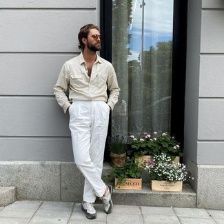 С чем носить белые классические брюки мужчине: Бежевая рубашка с длинным рукавом и белые классические брюки — отличный пример строгого мужского стиля в одежде. Создать стильный контраст с остальными элементами этого образа помогут серые кроссовки.