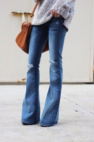 С чем носить синие рваные джинсы-клеш в 30 лет: Бежевый вязаный свободный свитер и синие рваные джинсы-клеш — выбор женщин, которые всегда в движении.