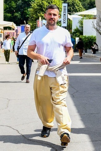 Модный лук: бежевый свитшот, белая футболка с круглым вырезом, желтые брюки чинос, черные кроссовки