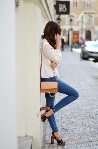С чем носить темно-синие джинсы скинни в жару: Белая шелковая блузка с длинным рукавом и темно-синие джинсы скинни — хорошая идея для простого, но модного образа. Очень удачно здесь будут смотреться черные кожаные босоножки на каблуке.