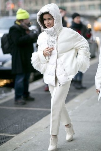 Как носить брюки-галифе с ботильонами: Белая куртка-пуховик с украшением и брюки-галифе — неотъемлемые вещи в гардеробе барышень с чувством стиля. В тандеме с этим луком наиболее гармонично смотрятся ботильоны.