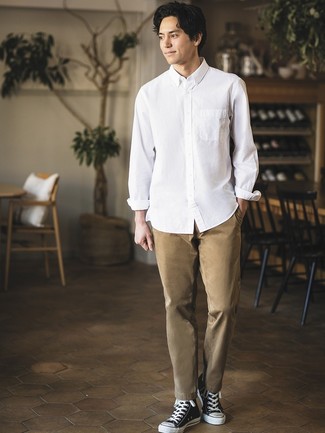 Модный лук: белая рубашка с длинным рукавом, светло-коричневые брюки чинос, черно-белые высокие кеды из плотной ткани
