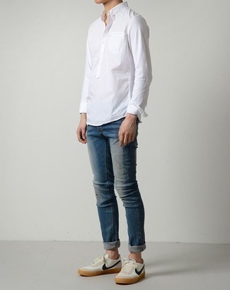 Модный лук: белая рубашка с длинным рукавом, синие рваные джинсы, бело-темно-синие низкие кеды из плотной ткани