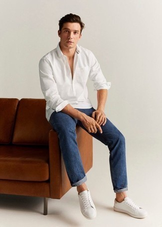 Как носить темно-синие джинсы с белыми кожаными низкими кедами мужчине в стиле кэжуал: Белая рубашка с длинным рукавом и темно-синие джинсы великолепно подходят для создания городского образа на каждый день. В сочетании с этим образом наиболее удачно смотрятся белые кожаные низкие кеды.