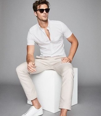 Модный лук: белая рубашка с коротким рукавом, бежевые брюки чинос, белые кожаные низкие кеды, темно-коричневые солнцезащитные очки