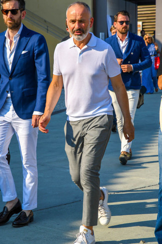 С чем носить бело-синюю футболку-поло мужчине лето в стиле кэжуал: Бело-синяя футболка-поло в паре с серыми брюками чинос подчеркнет твою индивидуальность. Белые кожаные низкие кеды — отличный выбор, чтобы завершить образ. Не стоит забывать о таком ансамбле, особенно когда на улице мучительная жара.
