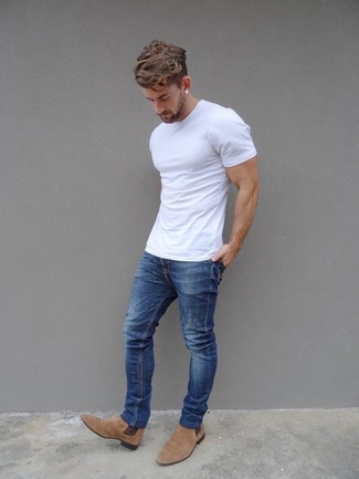 С чем носить синие джинсы в 30 лет мужчине в жару в стиле смарт-кэжуал: Белая футболка с круглым вырезом и синие джинсы прочно обосновались в гардеробе современных джентльменов, помогая создавать неприевшиеся и стильные луки. Такой образ легко обретает свежее прочтение в сочетании с светло-коричневыми замшевыми ботинками челси.