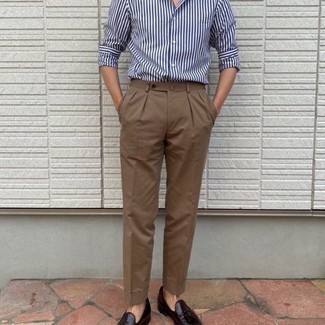 С чем носить темно-коричневые классические брюки в 30 лет мужчине в теплую погоду: Бело-темно-синяя рубашка с длинным рукавом в вертикальную полоску в паре с темно-коричневыми классическими брюками позволит создать модный и мужественный ансамбль. Любители экспериментов могут завершить образ темно-красными кожаными лоферами с кисточками, тем самым добавив в него чуточку строгости.