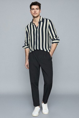 Модный лук: бело-темно-синяя рубашка с длинным рукавом в вертикальную полоску, черные брюки чинос, белые низкие кеды из плотной ткани