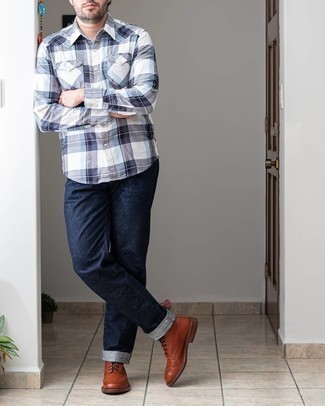 С чем носить темно-коричневые кожаные ботинки броги: Бело-темно-синяя рубашка с длинным рукавом в шотландскую клетку и темно-синие джинсы надежно закрепились в гардеробе современных мужчин, позволяя составлять запоминающиеся и стильные луки. Сделать образ изысканнее помогут темно-коричневые кожаные ботинки броги.