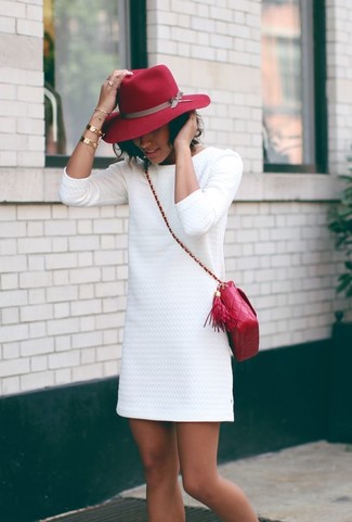 Модный лук: белое платье прямого кроя с рельефным рисунком, красная кожаная стеганая сумка через плечо, красная шерстяная шляпа, золотой браслет