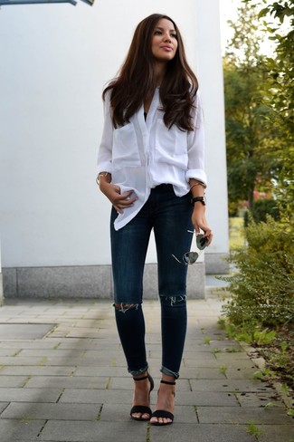 Модный лук: белая блуза на пуговицах, темно-синие рваные джинсы скинни, черные замшевые босоножки на каблуке, черные солнцезащитные очки