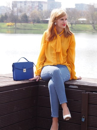 Модный лук: желтая блузка с длинным рукавом, бело-синие узкие брюки в клетку, белые кожаные туфли, синяя кожаная сумка-саквояж