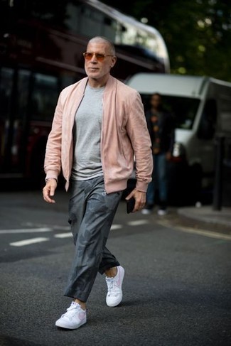С чем носить серые брюки чинос с принтом в 30 лет: Розовый бомбер и серые брюки чинос с принтом — must have вещи в гардеробе мужчин с чувством стиля. Переходя к обуви, можно завершить лук белыми кожаными низкими кедами.