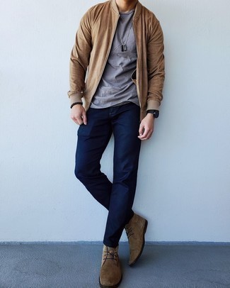 Модный лук: светло-коричневый бомбер, серая футболка с круглым вырезом, темно-синие джинсы, коричневые замшевые ботинки дезерты
