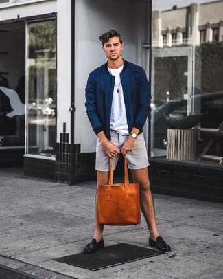 С чем носить темно-коричневую сумку в 20 лет мужчине в теплую погоду в стиле смарт-кэжуал: Если в одежде ты ценишь удобство и функциональность, темно-синий бомбер и темно-коричневая сумка — классный выбор для стильного повседневного мужского ансамбля. И почему бы не привнести в повседневный образ чуточку стильной строгости с помощью черных кожаных лоферов?