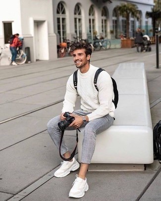 Модный мужской лук: белый вязаный свитер, серые брюки чинос в шотландскую клетку, бежевые кроссовки, черный рюкзак из плотной ткани