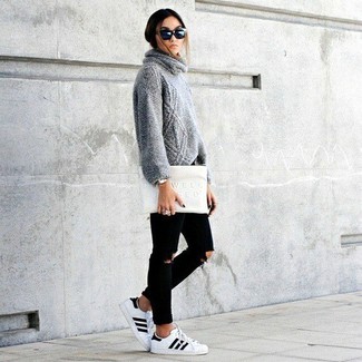 Модный лук: серый вязаный свитер, черные рваные джинсы скинни, белые низкие кеды, белый кожаный клатч