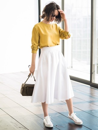 Модный лук: горчичная блузка с длинным рукавом, белая юбка-миди со складками, белые низкие кеды из плотной ткани, оливковая кожаная сумка через плечо