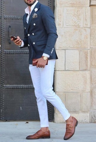 Как носить бело-синюю классическую рубашку с темно-синим пиджаком в вертикальную полоску мужчине: Темно-синий пиджак в вертикальную полоску и бело-синяя классическая рубашка позволят создать эффектный мужской образ. Такой образ обретает свежее прочтение в сочетании с коричневыми кожаными монками.