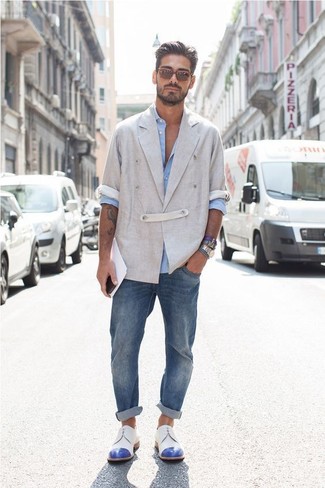 С чем носить серый льняной двубортный пиджак мужчине: Сочетание серого льняного двубортного пиджака и синих джинсов — великолепный пример привлекательного офисного стиля для джентльменов. Дополнив лук бело-синими кожаными туфлями дерби, можно получить потрясающий результат.
