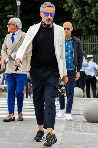 С чем носить кроссовки за 50 лет мужчине: Комбо из белого двубортного пиджака и черных брюк карго — идеальный офисный вариант для джентльменов. Поклонники незаезженных сочетаний могут дополнить образ кроссовками.