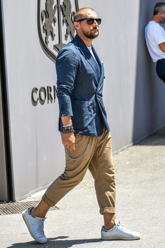 Какие брюки чинос носить с темно-сине-белым пиджаком в 30 лет в жару: Ансамбль из темно-сине-белого пиджака и брюк чинос смотрится очень привлекательно, разве нет? Создать стильный контраст с остальными элементами этого образа помогут белые кожаные низкие кеды.