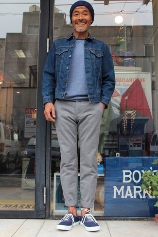 Как носить темно-синюю джинсовую куртку с серыми брюками чинос за 50 лет в теплую погоду: Сочетание темно-синей джинсовой куртки и серых брюк чинос — классная идея для воплощения мужского лука в стиле smart casual. Создать незабываемый контраст с остальными составляющими этого лука помогут темно-сине-белые низкие кеды из плотной ткани.