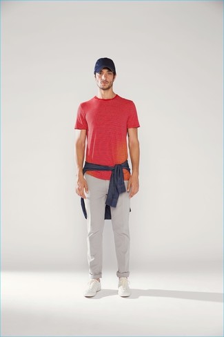 Как носить красную футболку с круглым вырезом с серыми брюками чинос в стиле кэжуал: Красная футболка с круглым вырезом и серые брюки чинос — беспроигрышный лук, если ты хочешь составить раскованный, но в то же время модный мужской лук. Белые кожаные низкие кеды становятся превосходным завершением твоего ансамбля.