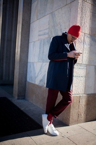 Как носить темно-красные брюки чинос с белыми плимсоллами в прохладную погоду: Темно-синее длинное пальто в сочетании с темно-красными брюками чинос однозначно будет привлекать внимание прекрасного пола. Почему бы не добавить в этот ансамбль немного легкости с помощью белых плимсоллов?