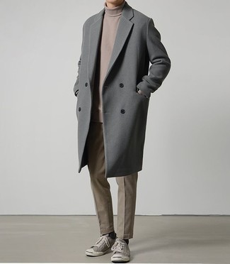 Как носить темно-серое длинное пальто с серыми низкими кедами из плотной ткани в 30 лет в прохладную погоду: Темно-серое длинное пальто и коричневые брюки чинос — прекрасный выбор для повседневного офисного лука. Закончив лук серыми низкими кедами из плотной ткани, ты привнесешь в него динамичность.