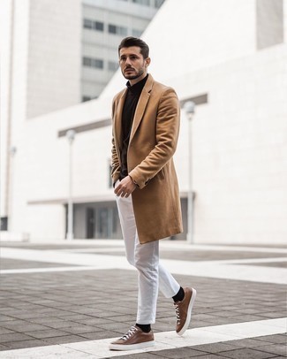 Как носить светло-коричневое длинное пальто с белыми брюками чинос: Светло-коричневое длинное пальто и белые брюки чинос — обязательные вещи в гардеробе парней с хорошим вкусом в одежде. Ты сможешь легко адаптировать такой лук к повседневным делам, надев коричневыми кожаными низкими кедами.