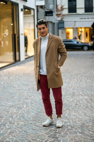 С чем носить темно-красные брюки чинос в 20 лет в прохладную погоду: Светло-коричневое длинное пальто и темно-красные брюки чинос — обязательные вещи в арсенале джентльменов с чувством стиля. Если тебе нравится экспериментировать, на ноги можешь надеть белые кроссовки.