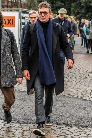 С чем носить черное длинное пальто за 50 лет в прохладную погоду: Черное длинное пальто выглядит прекрасно в паре с серыми классическими брюками. Этот лук чудесно дополнят серые замшевые низкие кеды.