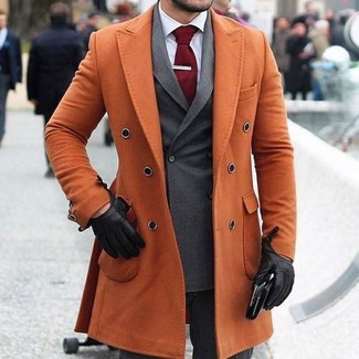С чем носить оранжевое длинное пальто в холод в деловом стиле: Сочетание оранжевого длинного пальто и темно-серых классических брюк поможет создать модный и в то же время элегантный образ.