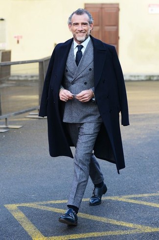 С чем носить темно-синий шелковый галстук за 50 лет мужчине в деловом стиле: Несмотря на то, что этот лук выглядит довольно сдержанно, сочетание черного длинного пальто и темно-синего шелкового галстука всегда будет по вкусу стильным мужчинам, но также пленяет при этом сердца женщин. Закончи образ черными кожаными монками с двумя ремешками, если не хочешь, чтобы он получился слишком претенциозным.