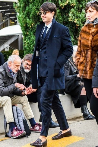 С чем носить коричневые кожаные плетеные лоферы в 30 лет мужчине в холод: Сочетание темно-синего длинного пальто и темно-синего костюма в вертикальную полоску — отличный пример строгого мужского стиля. Очень стильно здесь выглядят коричневые кожаные плетеные лоферы.