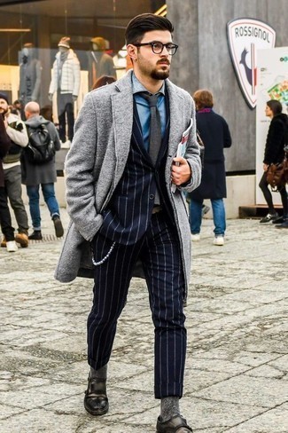 С чем носить темно-серый галстук в 30 лет мужчине в деловом стиле: Несмотря на то, что этот лук выглядит довольно сдержанно, сочетание серого длинного пальто и темно-серого галстука является постоянным выбором стильных мужчин, неминуемо пленяя при этом сердца прекрасных дам. Почему бы не добавить в этот лук толику фривольности с помощью темно-серых кожаных монок с двумя ремешками?