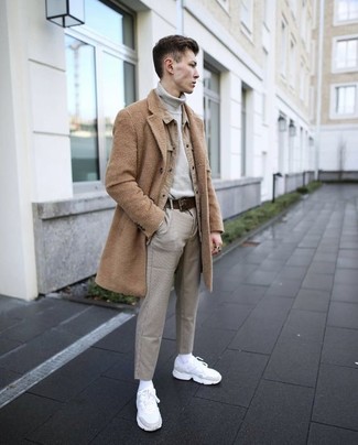 Как носить светло-коричневое длинное пальто с серыми брюками чинос: Светло-коричневое длинное пальто в паре с серыми брюками чинос — нескучный выбор для джентльменов, работающих в офисе. Почему бы не привнести в этот образ чуточку легкой небрежности с помощью белых кроссовок?