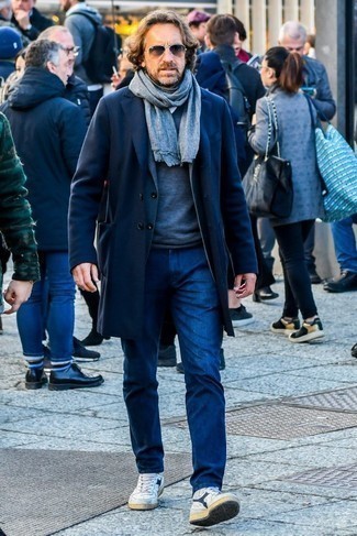 С чем носить кожаные высокие кеды за 40 лет мужчине в стиле смарт-кэжуал: Темно-синее длинное пальто и темно-синие джинсы — прекрасный вариант для воплощения мужского ансамбля в стиле смарт-кэжуал. Если тебе нравится экспериментировать, на ноги можешь надеть кожаные высокие кеды.