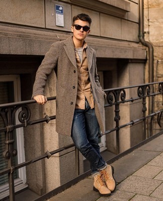 Как носить темно-коричневое длинное пальто с узором "в ёлочку" с темно-синими джинсами в 30 лет: Комбо из темно-коричневого длинного пальто с узором "в ёлочку" и темно-синих джинсов может стать замечательным образом для офиса. Ты сможешь легко адаптировать такой образ к повседневным нуждам, закончив его светло-коричневыми кожаными рабочими ботинками.