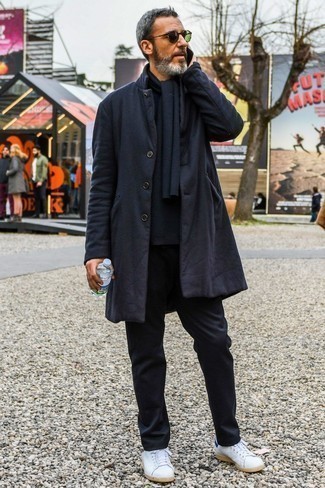 Модный лук: черное длинное пальто, черный свитер с круглым вырезом, черные брюки чинос, белые кожаные низкие кеды