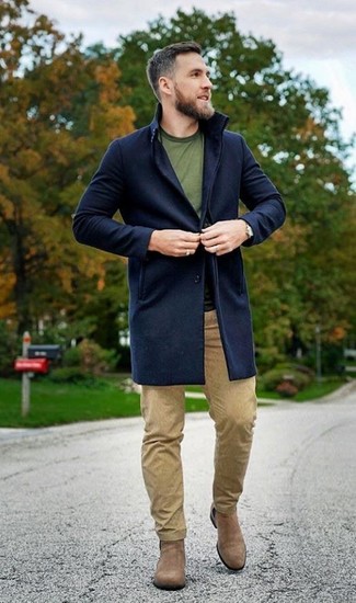 Модный лук: темно-синее длинное пальто, оливковая футболка с круглым вырезом, светло-коричневые брюки чинос, светло-коричневые замшевые ботинки челси