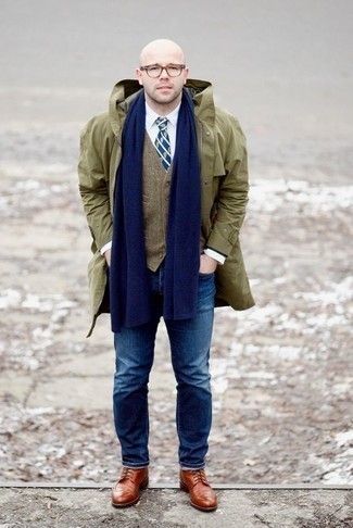 С чем носить темно-зеленый дождевик мужчине в прохладную погоду: Если ты любишь одеваться модно, чувствуя себя при этом комфортно и расслабленно, стоит примерить это сочетание темно-зеленого дождевика и темно-синих джинсов. Почему бы не добавить в повседневный лук чуточку нарядности с помощью табачных кожаных ботинок броги?