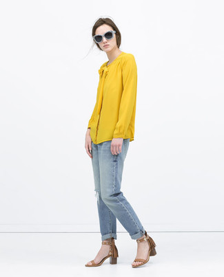 С чем носить желтую блузку в 20 лет в жару: Ансамбль из желтой блузки и голубых рваных джинсов-бойфрендов - самый простой из возможных образов для активного досуга. Весьма гармонично здесь выглядят коричневые кожаные босоножки на каблуке.