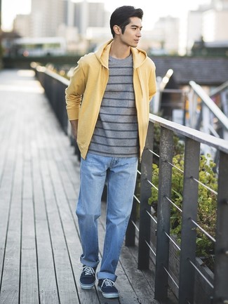 Модный лук: желтый худи, серая футболка с круглым вырезом в горизонтальную полоску, голубые джинсы, темно-синие низкие кеды из плотной ткани