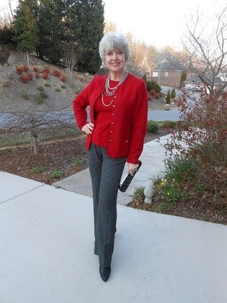 С чем носить красный кардиган за 50 лет женщине: Красный кардиган в паре с темно-серыми классическими брюками позволит подчеркнуть твою индивидуальность. В тандеме с этим луком идеально будут выглядеть черные кожаные ботильоны.